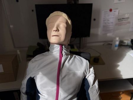 Reanimationspuppe im Sonnenlicht sitzend auf Bürostuhl (Puppe hat auch Arme und Beine)