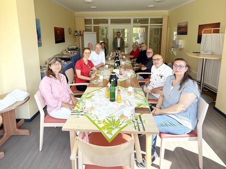 Mitarbeiterinnen und Mitarbeiter sitzen gemeinsam zusammen bei einem Frühstück.